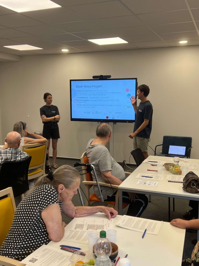 Two people explaining the silver ways project in front of a screen 