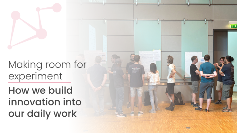 Gruppe von Menschen steht vor mehreren an der Wand befestigten Plakaten in einem hellen Raum mit Holzboden.