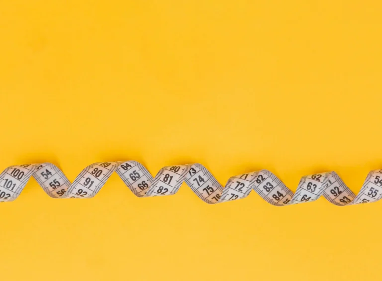 Wavy measuring tape with centimeter and inch markings on yellow background