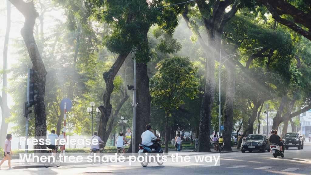 Sunlight filtering through large trees lining a city street with people walking and vehicles moving